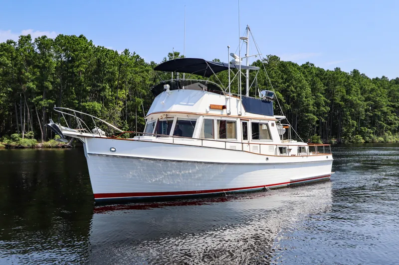 Slide: The Image of 1989 Grand Banks 42 Classic yacht cruising on a serene river with lush green forest backdrop. - 10