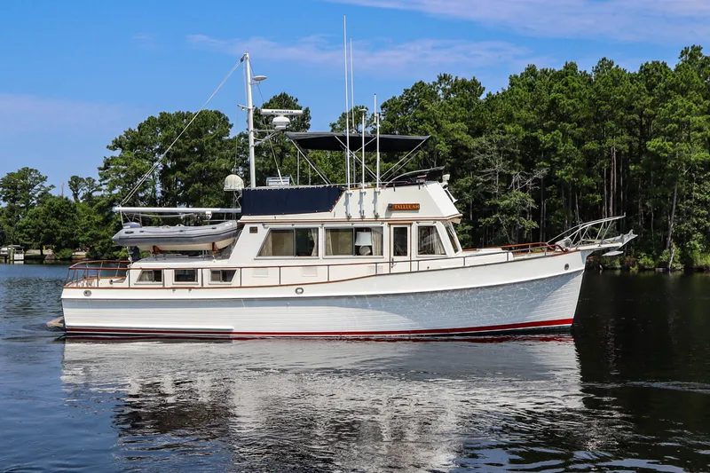 Slide: The Image of 1989 Grand Banks 42 Classic yacht on calm water, surrounded by lush trees. - 2