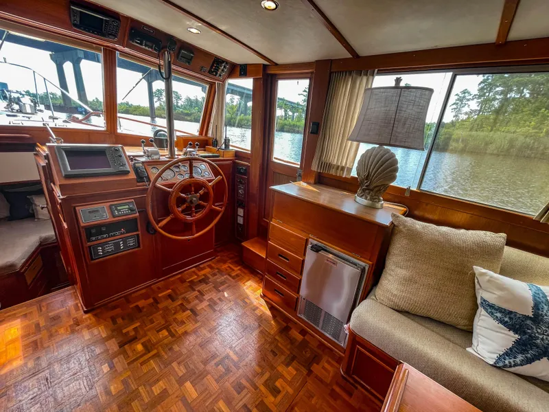 Slide: The Image of 1989 Grand Banks 42 Classic yacht interior with wooden helm, cozy seating, and scenic water view. - 20