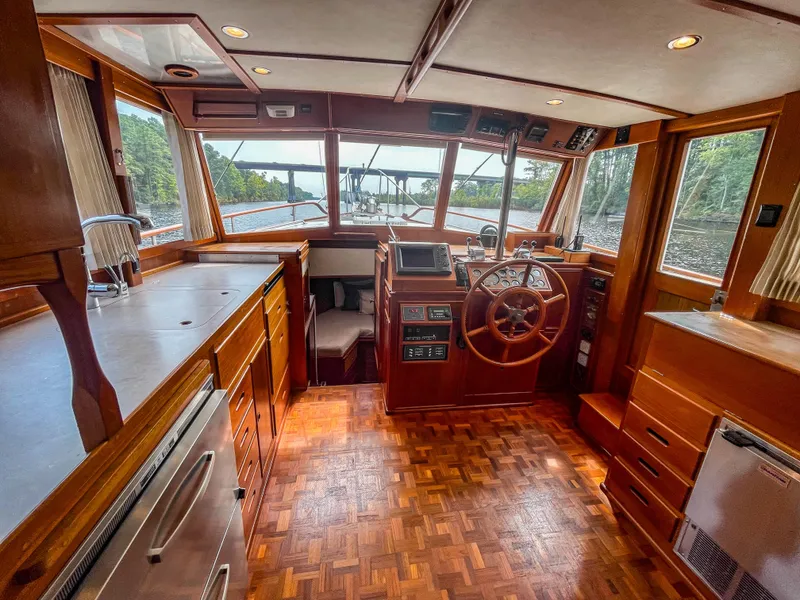 Slide: The Image of 1989 Grand Banks 42 Classic yacht interior with wooden helm, spacious cabin, and panoramic windows. - 26
