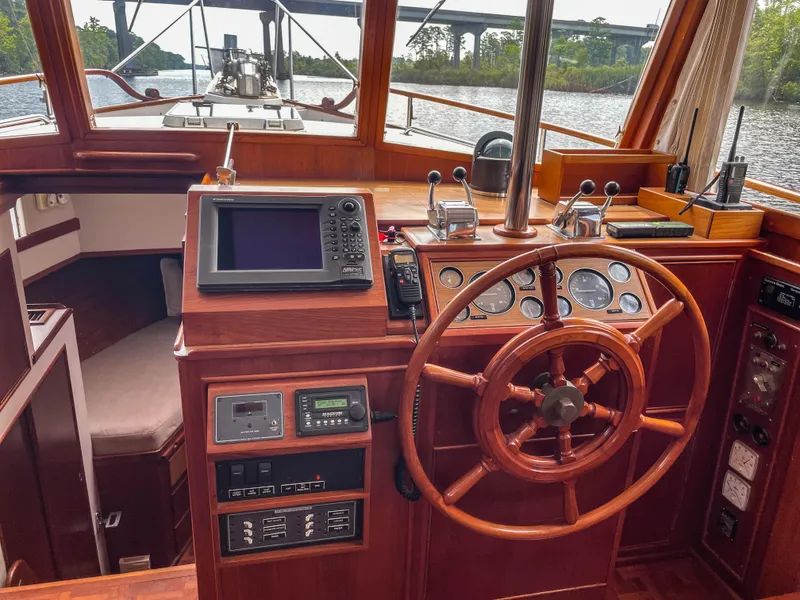 Slide: The Image of 1989 Grand Banks 42 Classic helm with wooden wheel, navigation instruments, and river view. - 29