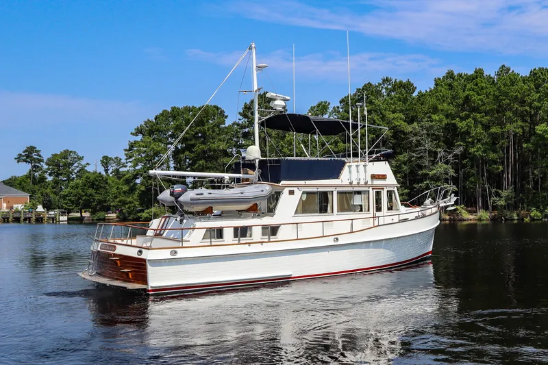 Slide: The Image of 1989 Grand Banks 42 Classic yacht on a serene lake with lush green trees. - 3