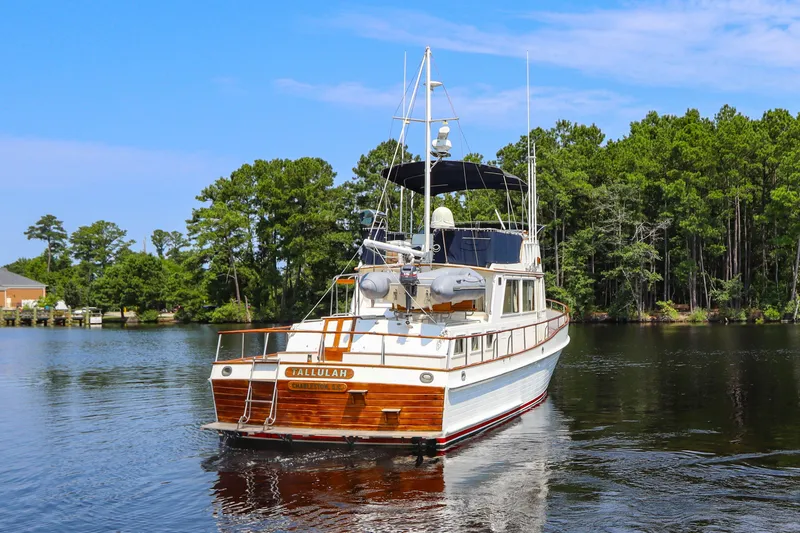 Slide: The Image of 1989 Grand Banks 42 Classic yacht cruising on a serene lake with lush green trees. - 4