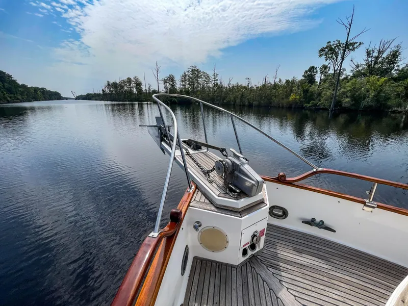 Slide: The Image of 1989 Grand Banks 42 Classic yacht on serene river with lush greenery and blue sky. - 44