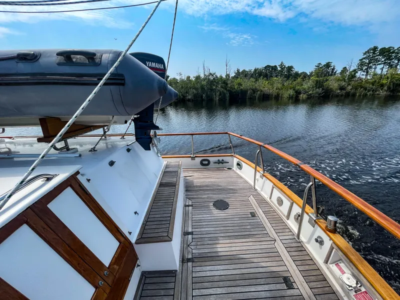 Slide: The Image of 1989 Grand Banks 42 Classic yacht deck with wooden finish, docked by a serene river. - 48