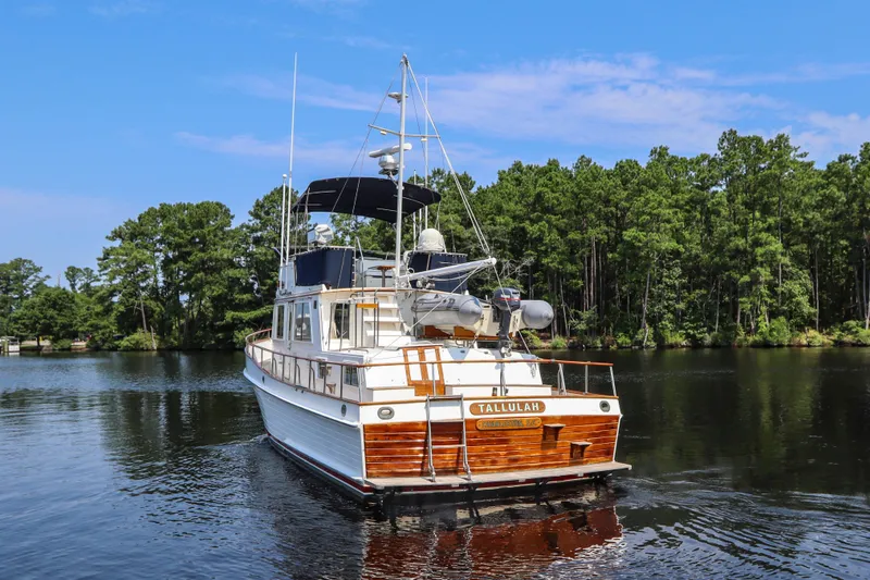 Slide: The Image of 1989 Grand Banks 42 Classic yacht on a serene lake with lush green trees. - 5