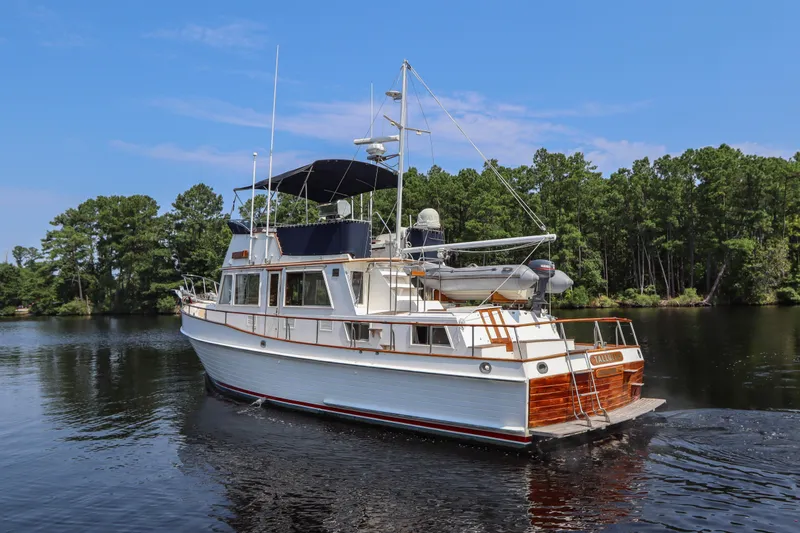 Slide: The Image of 1989 Grand Banks 42 Classic yacht cruising on a serene lake with lush green trees. - 6