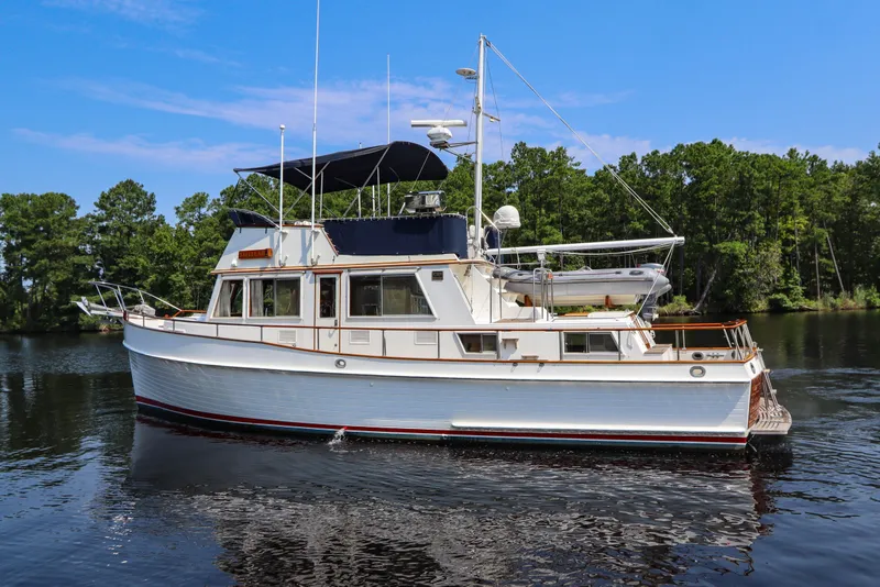 Slide: The Image of 1989 Grand Banks 42 Classic yacht on calm water, surrounded by lush greenery. - 7