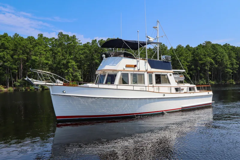Slide: The Image of 1989 Grand Banks 42 Classic yacht on calm water, surrounded by lush green trees. - 9