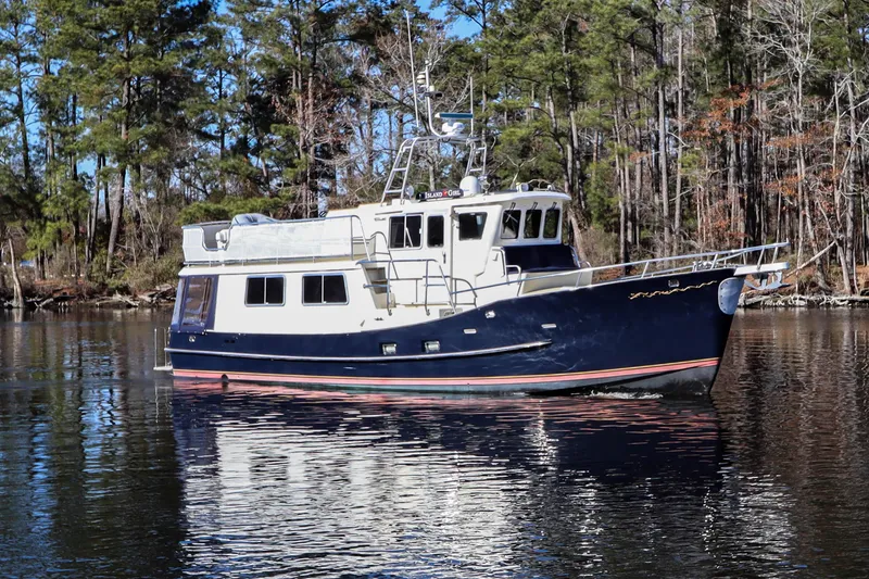 Slide: The Image of Cherubini Independence 2000 boat on calm water, surrounded by trees. - 10
