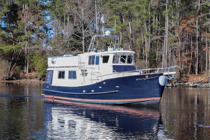 Slide: The Image of Cherubini Independence 2000 boat on calm water, surrounded by trees. - 11