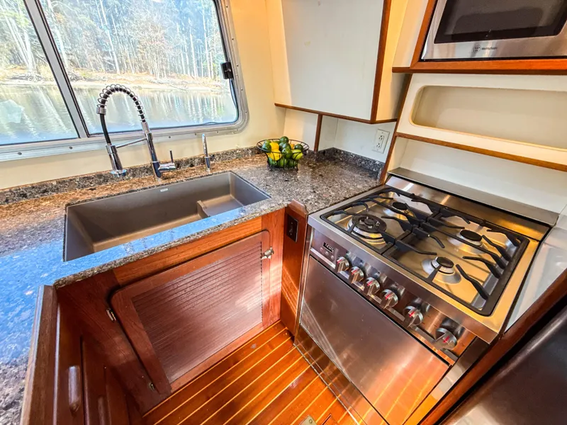 Slide: The Image of Cherubini Independence 2000 yacht kitchen with stainless steel sink, gas stove, and window view. - 25