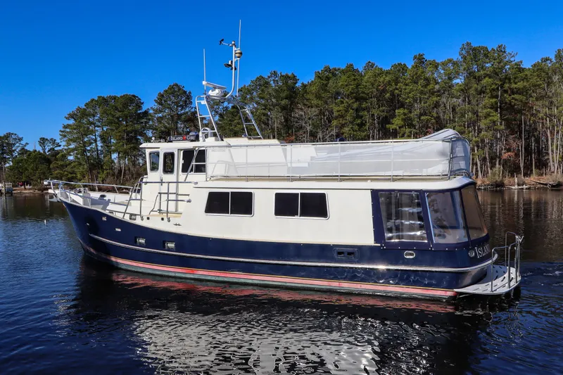 Slide: The Image of Cherubini Independence 2000 yacht on a serene lake with forest backdrop. - 4