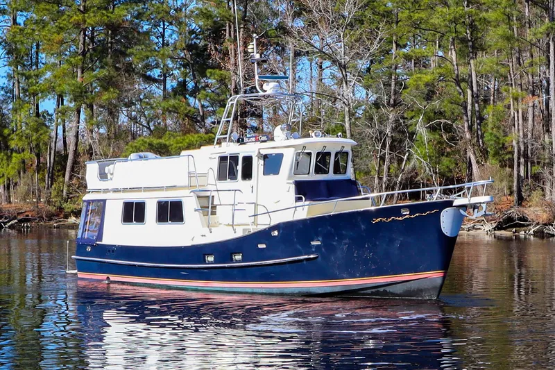 Slide: The Image of Cherubini Independence 2000 boat on a calm lake, surrounded by trees. - 5