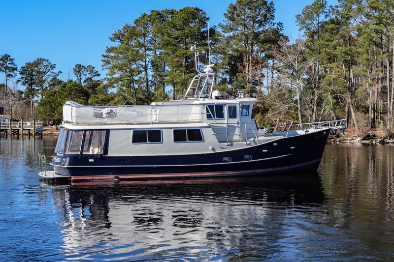 Slide: The Image of Cherubini Independence 2000 yacht on a serene lake with lush trees in the background. - 6