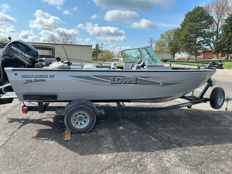 Slide: The Image of 2013 Lowe 185 Pro Series fishing boat on trailer, parked outdoors under a cloudy sky. - 1