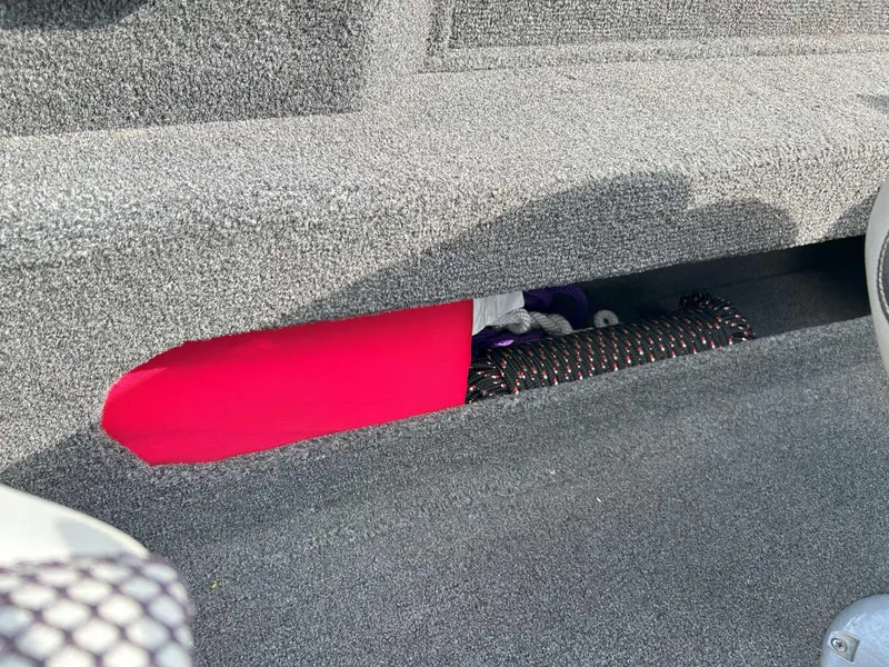 Slide: The Image of Storage compartment in a 2013 Lowe 185 Pro Series boat with red and black items. - 11