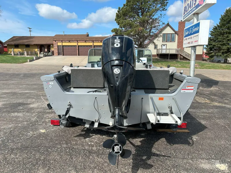 Slide: The Image of 2013 Lowe 185 Pro Series boat with outboard motor, parked outdoors on a sunny day. - 2