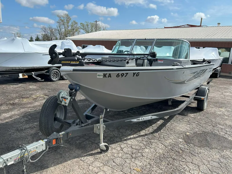 Slide: The Image of 2013 Lowe 185 Pro Series boat on trailer, parked outdoors under a partly cloudy sky. - 4