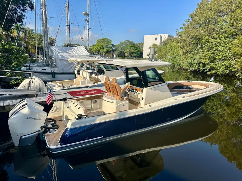 The Image of 2025 Chris-Craft Catalina boat docked on calm water, surrounded by lush greenery. - 0