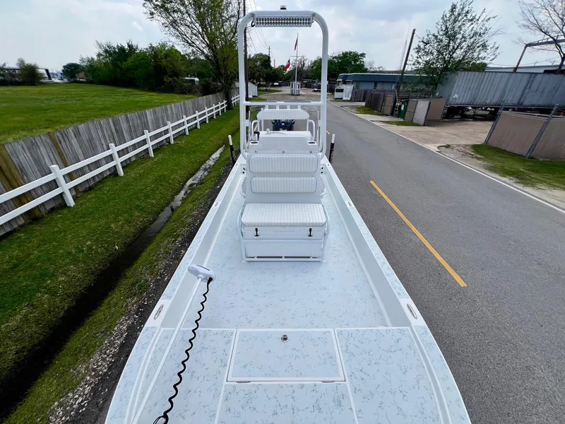 Slide: The Image of 2017 Shallow Sport 24 Sport boat on road, white fence, overcast sky. - 15