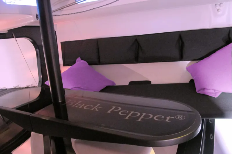 Slide: The Image of Modern Black Pepper yacht interior with purple cushions, sleek design, and branded table, model Code# 2025. - 10