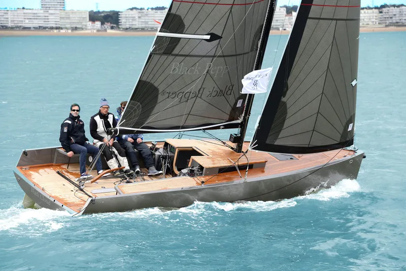 Slide: The Image of Sleek Black Pepper Code# sailboat gliding on water, 2025 model, with crew onboard. - 8