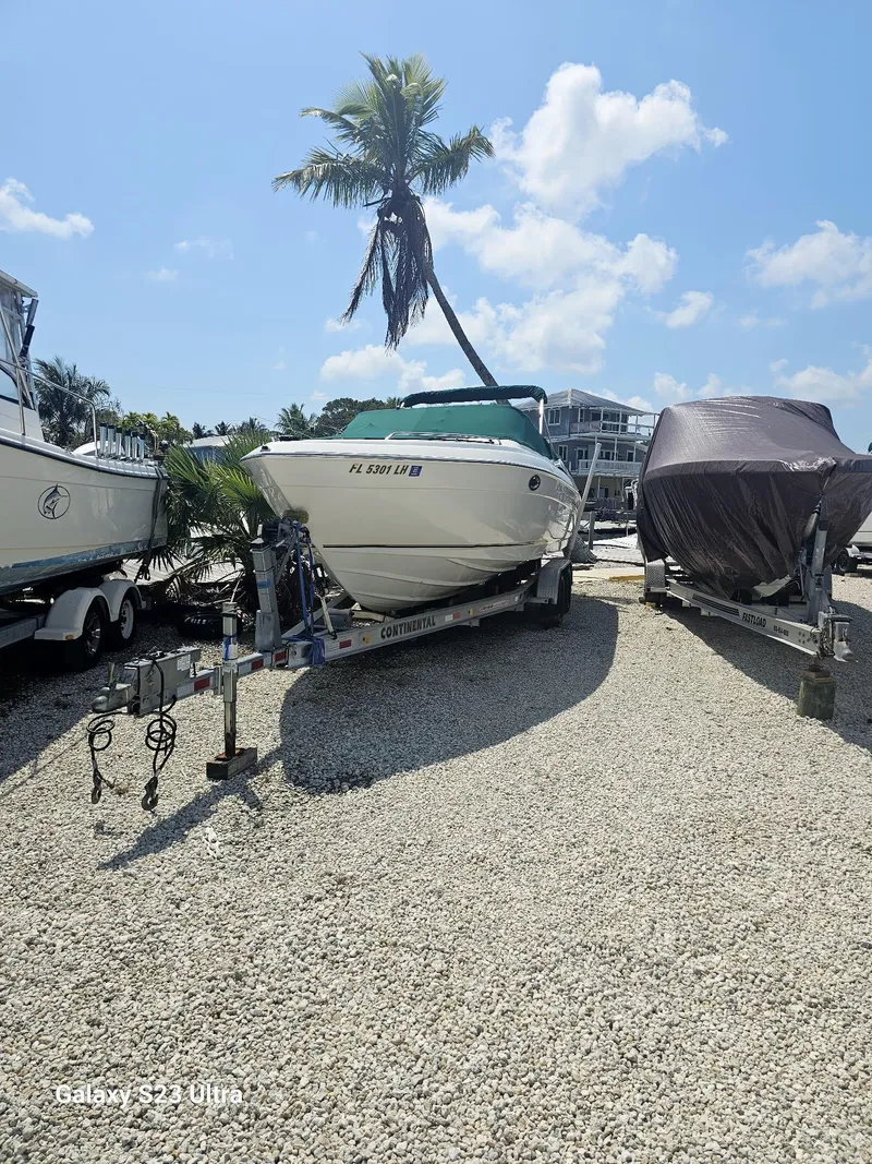 Slide: The Image of 2000 Regal 2800 LSR boat on trailer, parked under a palm tree, sunny day. - 2
