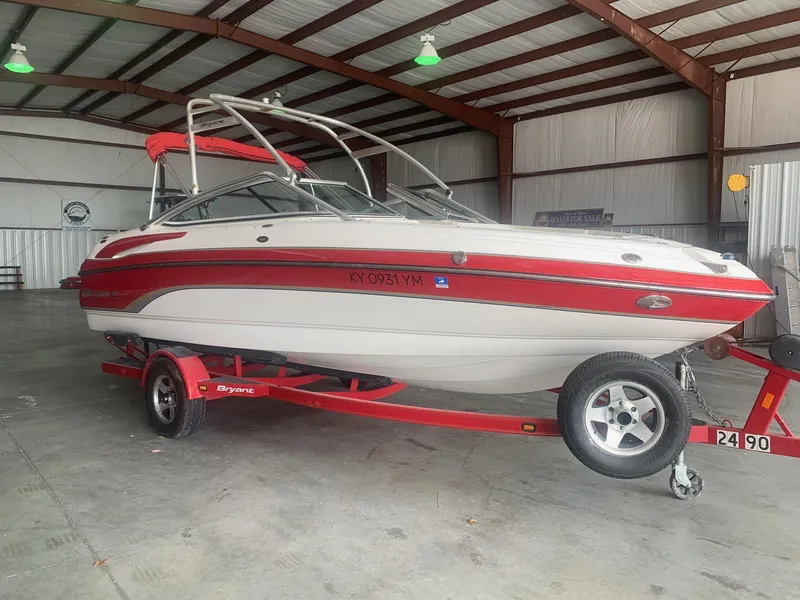 Slide: The Image of 2006 Bryant 206 BR boat in a warehouse, red and white design, on a trailer. - 1