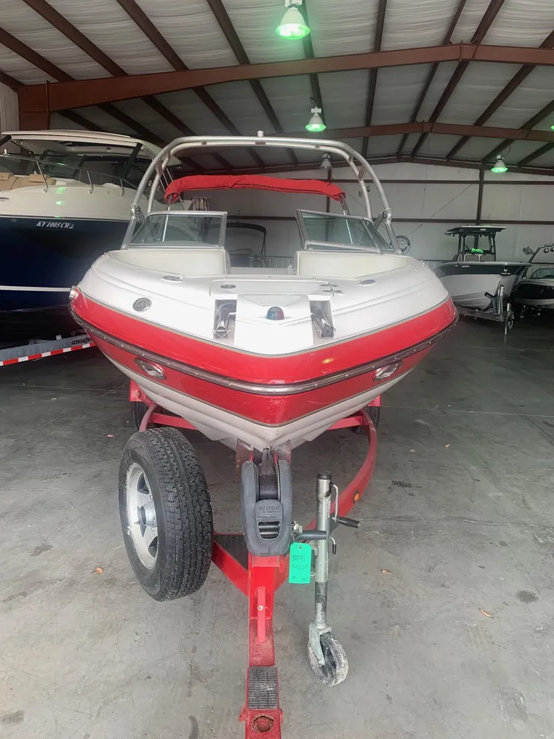 Slide: The Image of 2006 Bryant 206 BR boat in storage, red and white exterior, on a trailer. - 2