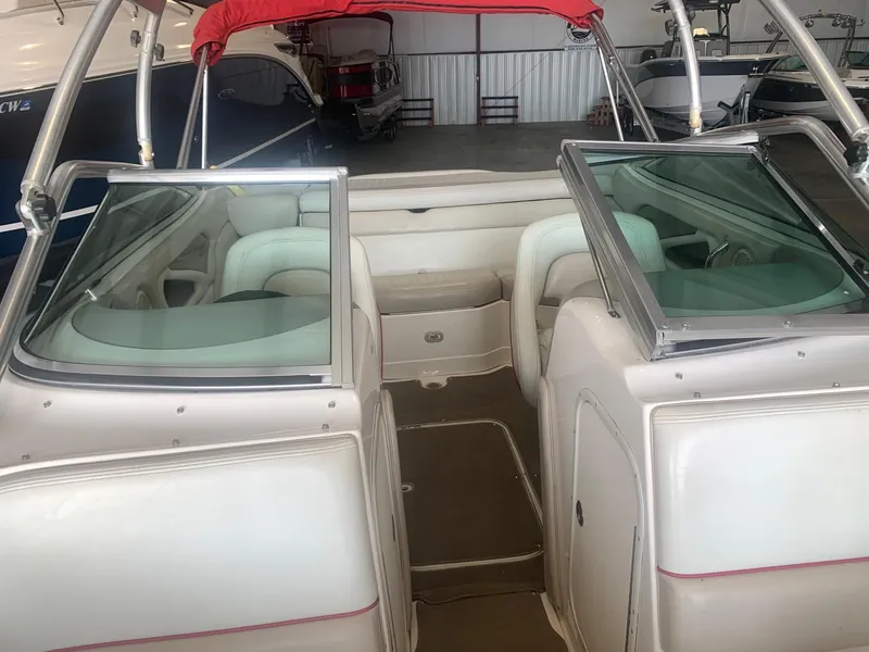 Slide: The Image of 2006 Bryant 206 BR boat interior with white seating and red canopy in a storage facility. - 34