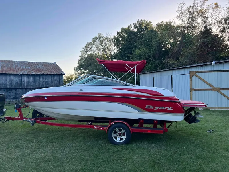 Slide: The Image of 2006 Bryant 206 BR boat on trailer, red and white, parked on grass near barn. - 4