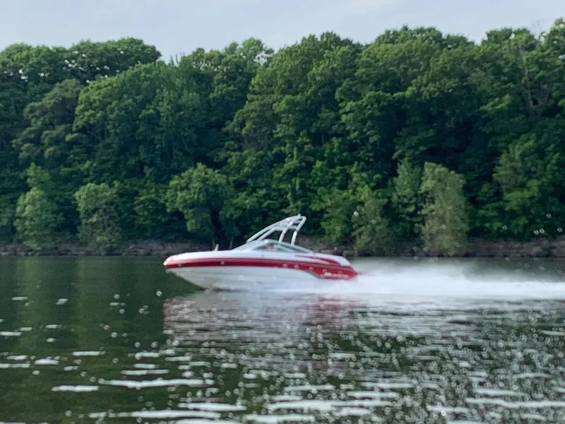 Slide: The Image of 2006 Bryant 206 BR speedboat cruising on a lake with lush green forest backdrop. - 7