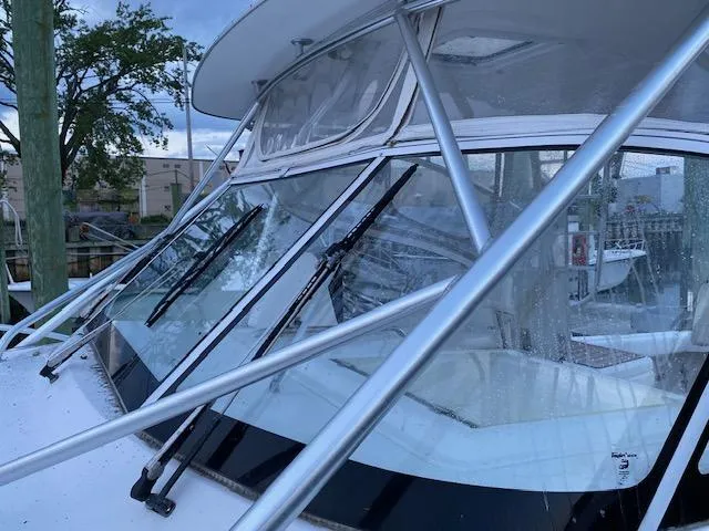 Slide: The Image of 2006 Luhrs 28 Open boat with windshield and metal framework, docked near trees. - 2