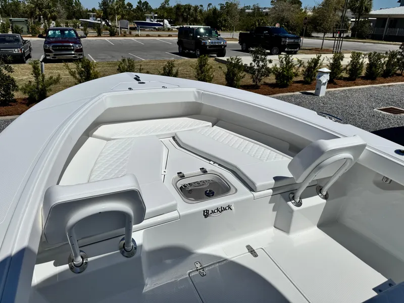 Slide: The Image of 2025 BlackJack 256 Coastal boat interior with seating and storage, parked outdoors. - 13
