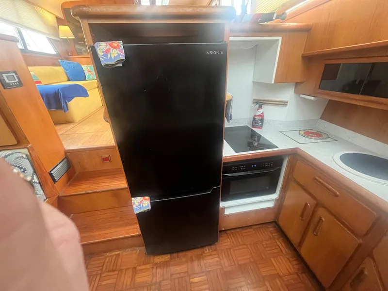 Slide: The Image of 1987 Jefferson 42 SE Sundeck Motor Yacht kitchen with black fridge and wooden cabinetry. - 27