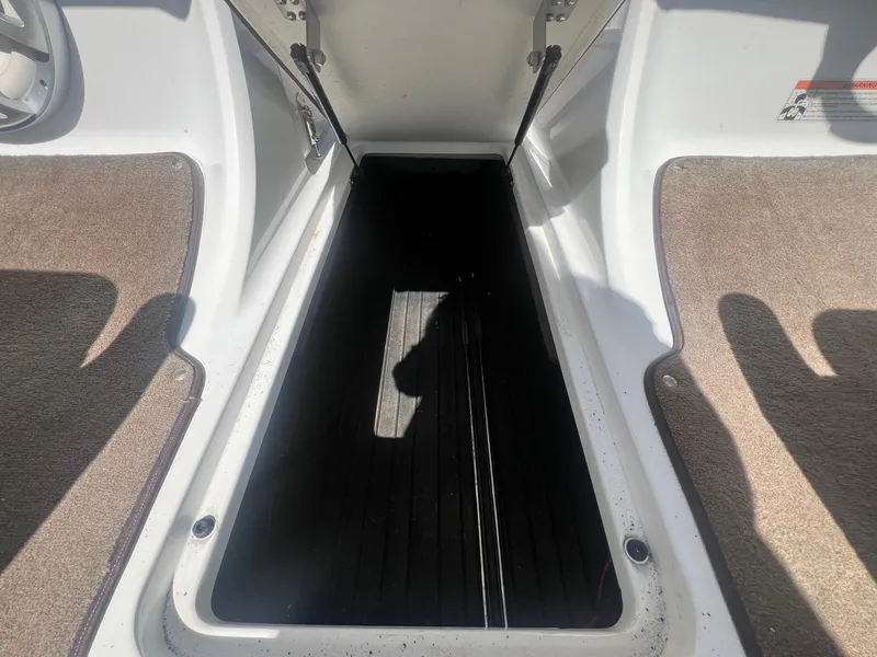 Slide: The Image of Open storage compartment on a 2007 Cobalt 232 boat, with carpeted flooring. - 22
