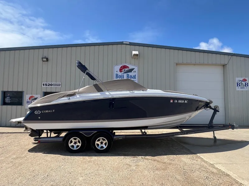 Slide: The Image of 2007 Cobalt 232 boat on trailer outside Boji Boat building under clear sky. - 37