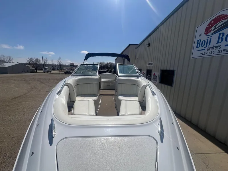 Slide: The Image of 2007 Cobalt 232 boat with white seating, parked near a building under a clear blue sky. - 7