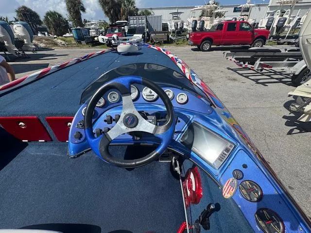 Slide: The Image of 2006 Storm Boats 22 dashboard with blue steering wheel and gauges, parked outdoors. - 5