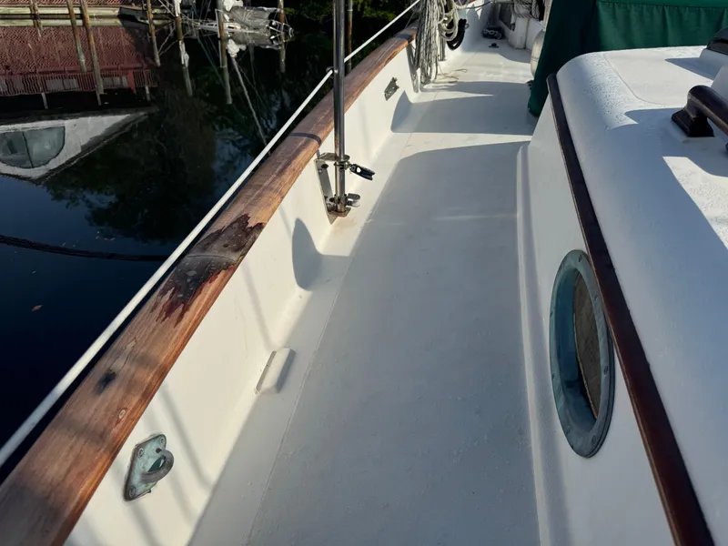 Slide: The Image of 1989 Hans Christian 43T yacht deck with wooden railings and porthole, reflecting on calm water. - 14