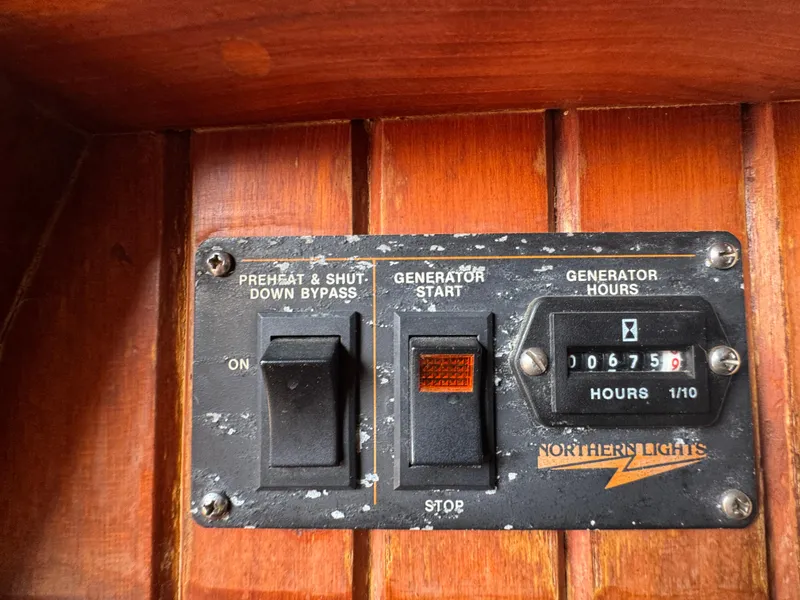 Slide: The Image of Control panel of a 1989 Hans Christian 43T boat, featuring generator switches and hour meter. - 35
