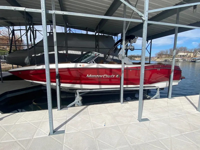 Slide: The Image of 2020 MasterCraft X26 boat in red, docked under a covered marina. - 1