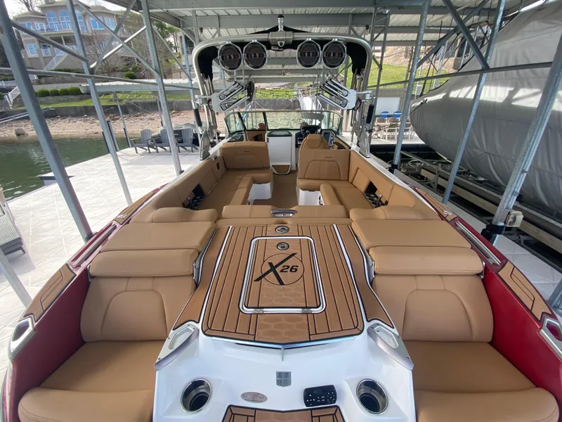Slide: The Image of 2020 MasterCraft X26 boat with luxurious tan seating and sleek design in a docked setting. - 10