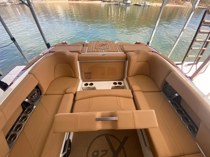 Slide: The Image of 2020 MasterCraft X26 boat interior with tan seating and cup holders, docked by the water. - 14