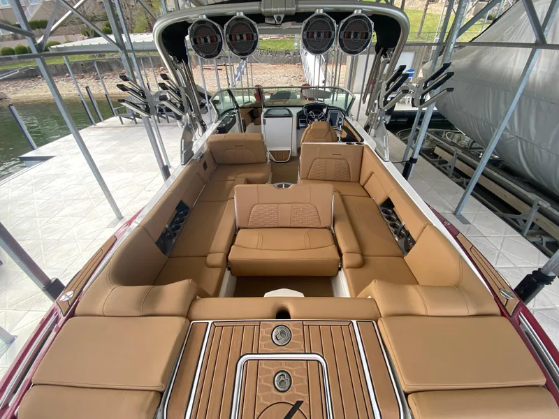 Slide: The Image of 2020 MasterCraft X26 boat interior with tan seating and sleek design in a docked setting. - 15