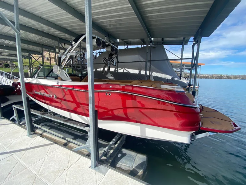 Slide: The Image of 2020 MasterCraft X26 boat in red, docked under a covered marina. - 2