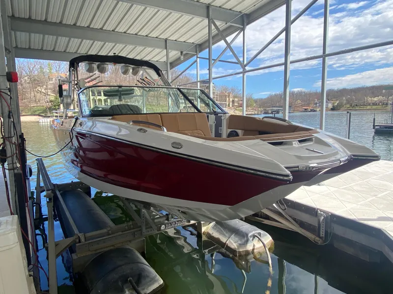 Slide: The Image of 2020 MasterCraft X26 boat docked in a covered marina, featuring a sleek red and white design. - 3