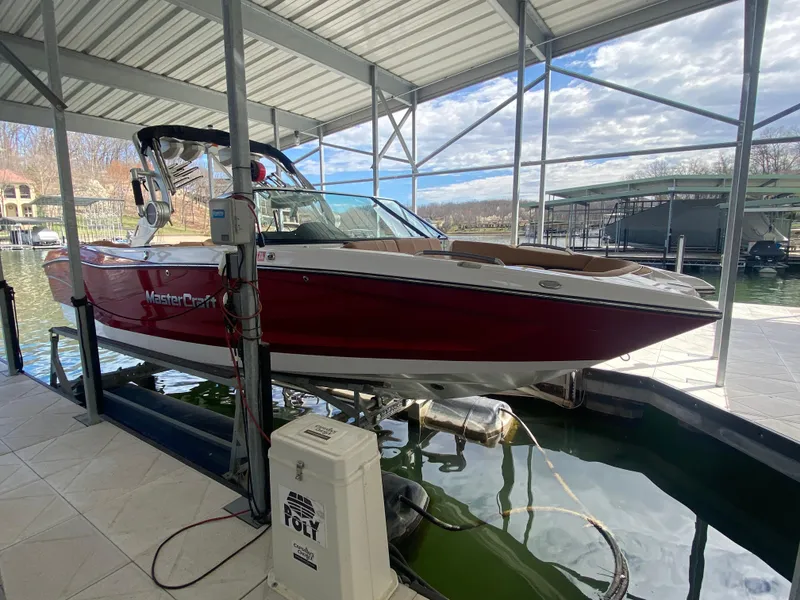 Slide: The Image of 2020 MasterCraft X26 boat in dock, red and white, under covered marina. - 4