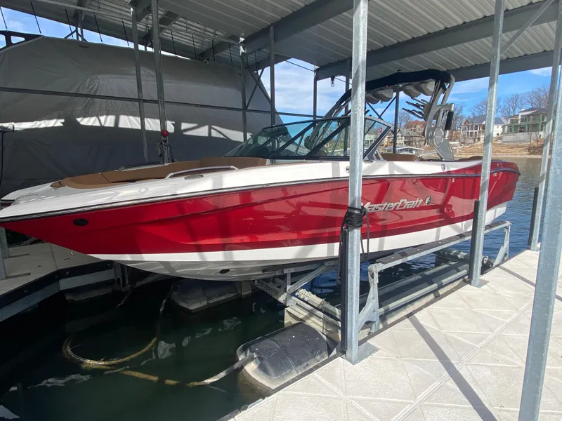 Slide: The Image of 2020 MasterCraft X26 boat in red, docked under a covered marina. - 9